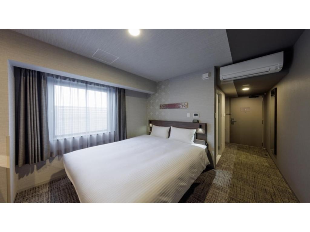 ein Schlafzimmer mit einem weißen Bett und einem Fenster in der Unterkunft Smile Hotel Kanazawa Nishiguchi Ekimae - Vacation STAY 11469v in Kanazawa