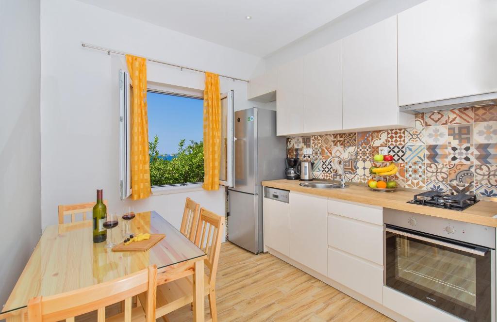 cocina con armarios blancos y mesa de madera en Apartments Roza, en Mlini