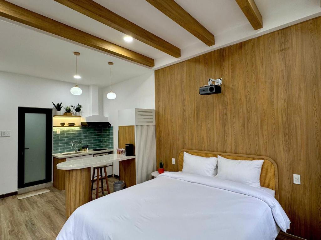 a bedroom with a white bed and a kitchen at Chạm's Hotel & Homestay in Ho Chi Minh City