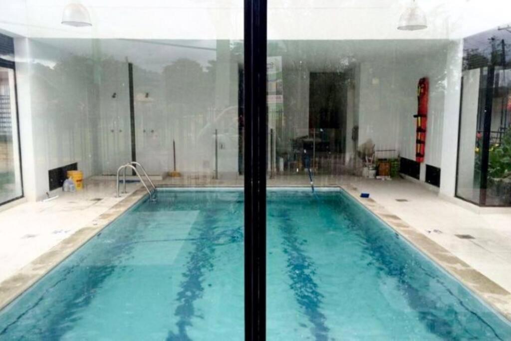 a swimming pool in a building with a large window at Acogedor Apartamento Loft en Club House en Cajicá in Cajicá