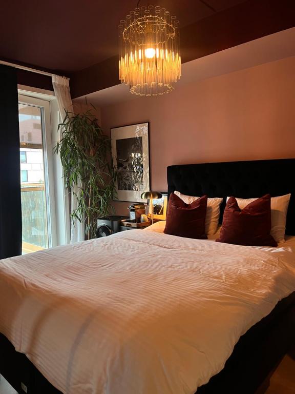 a bedroom with a large bed and a chandelier at Sunny apartment close to the sea in Oslo