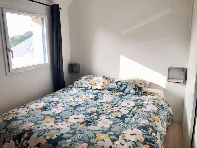 una camera da letto con un letto con un piumone floreale e una finestra di Le Galion Beach a Le Croisic