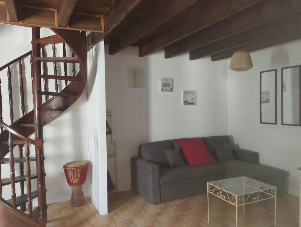 a living room with a gray couch and a staircase at La fermette de Chandigon in Antran