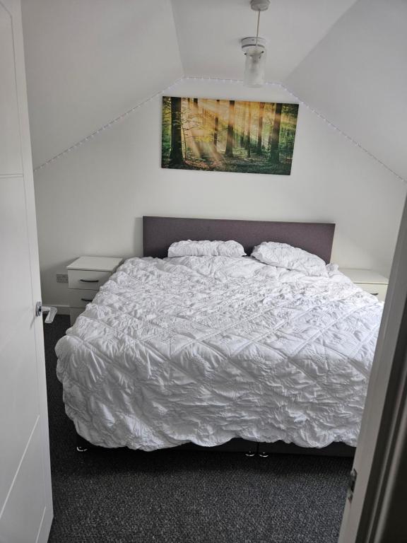a bedroom with a white bed and a painting on the wall at Northampton RoomKey in Northampton