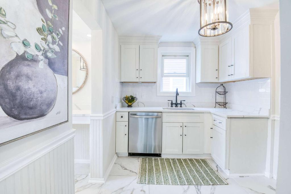a kitchen with white cabinets and a sink and a vase at Farmhouse Fresh 4BR Retreat in University Heights