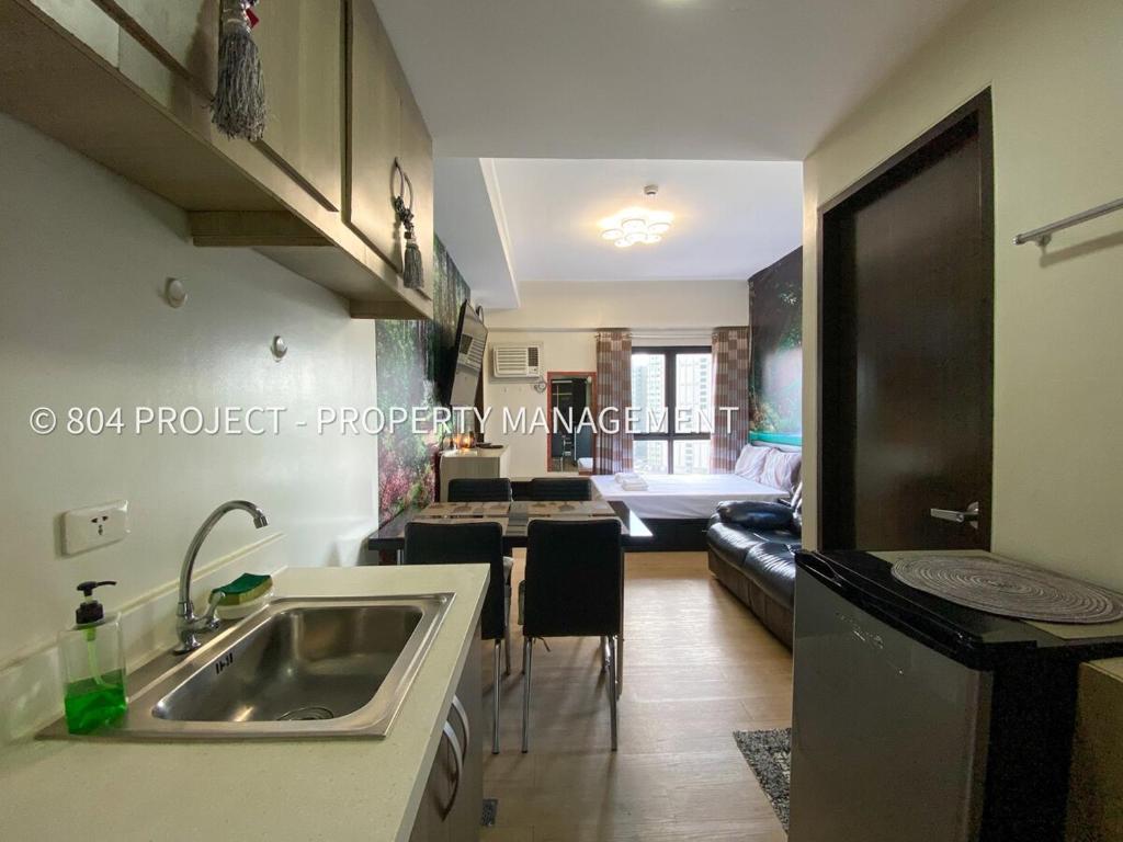 a kitchen with a sink and a living room at 1BR at Vinia Residences, North EDSA, QC in Manila