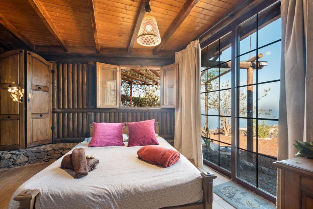 Un dormitorio con una cama con almohadas rosas y una ventana. en Finca rural House Tenerife Relax And Enjoy, en La Corujera