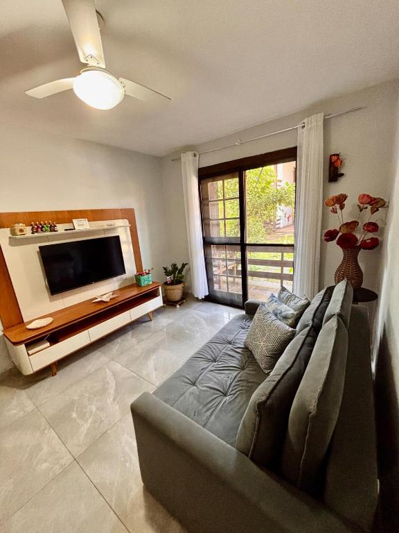 a living room with a couch and a flat screen tv at Casa térrea em condomínio à 500m da praia do Peró in Cabo Frio