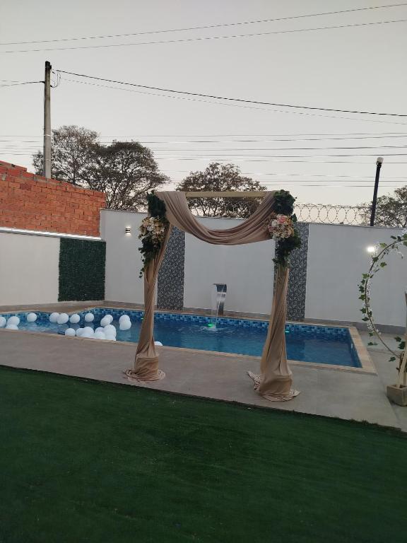 a gazebo with flowers on it next to a pool at Chácara Recanto JJ in Sorocaba