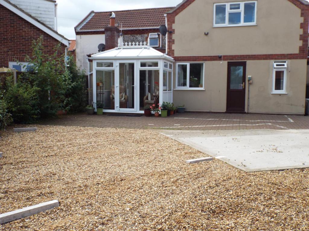 a house with a white porch and a driveway at Mount Lavinia in Sheringham