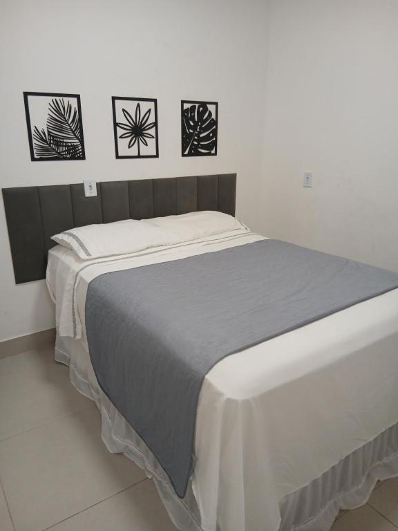 a bed in a bedroom with three pictures on the wall at Apartamento á 1200m da Praia de Itapua in Vila Velha