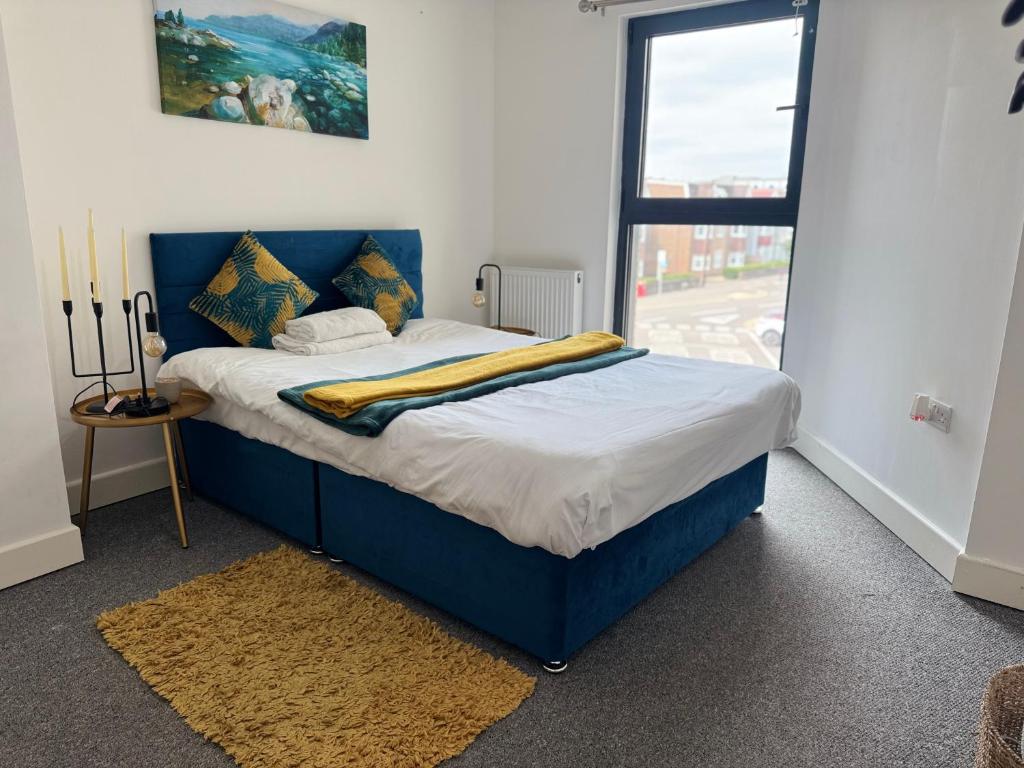 a blue bed in a room with a window at Heathrow central suites in Colnbrook