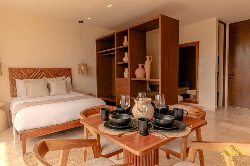 a bedroom with a bed and a table with glasses at Peregrina Tulum Lux Aparthotel in Tulum