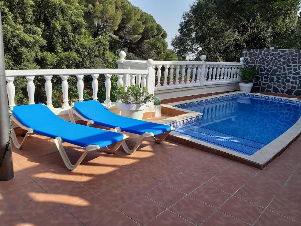 a pool with two chairs and a table next to it at casa vacacional con piscina privada in Sant Cebrià de Vallalta