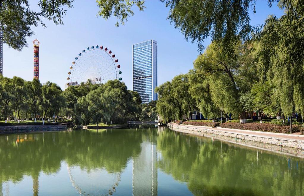 a park with a river and a ferris wheel in the background at Hyatt Regency Changchun in Changchun
