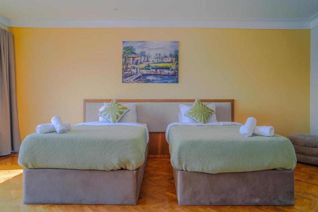 Dos camas en una habitación con paredes amarillas. en Adorable Apartment with stunning Nile view, en El Cairo
