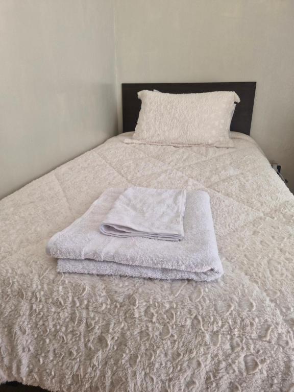 a white bed with a white towel on it at Habitación con baño privado y entrada independiente in La Serena