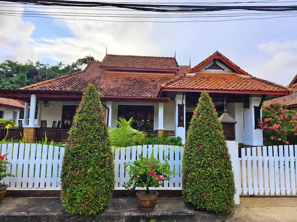 a white fence in front of a house with trees at Secure 3 Bedroom Villa near beach in Kamala Beach