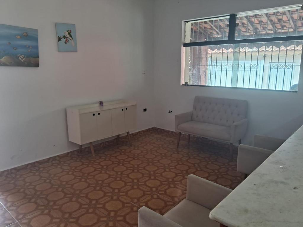 a room with a chair and a table and a window at Tati casa in Peruíbe
