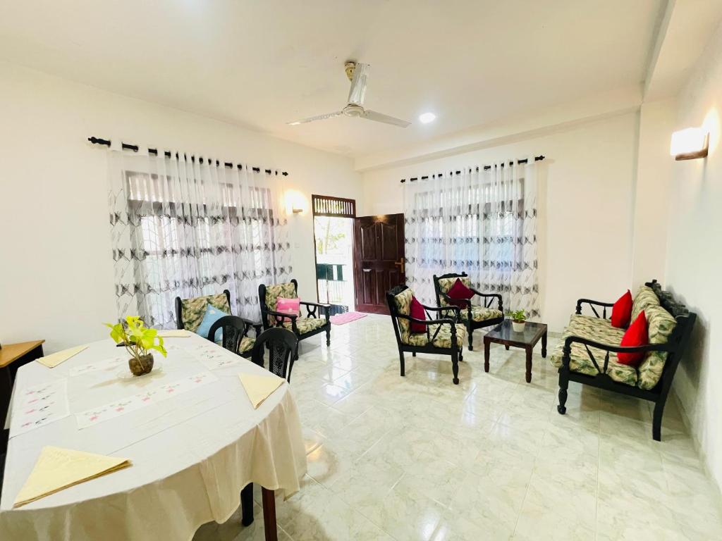 a dining room with a white table and chairs at Kenashi Green Villa in Weligama