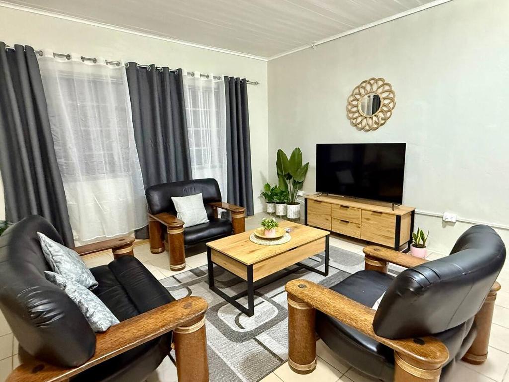 un soggiorno con mobili in pelle e una TV a schermo piatto di 2 Bedroom Unit Near City Center a Suva