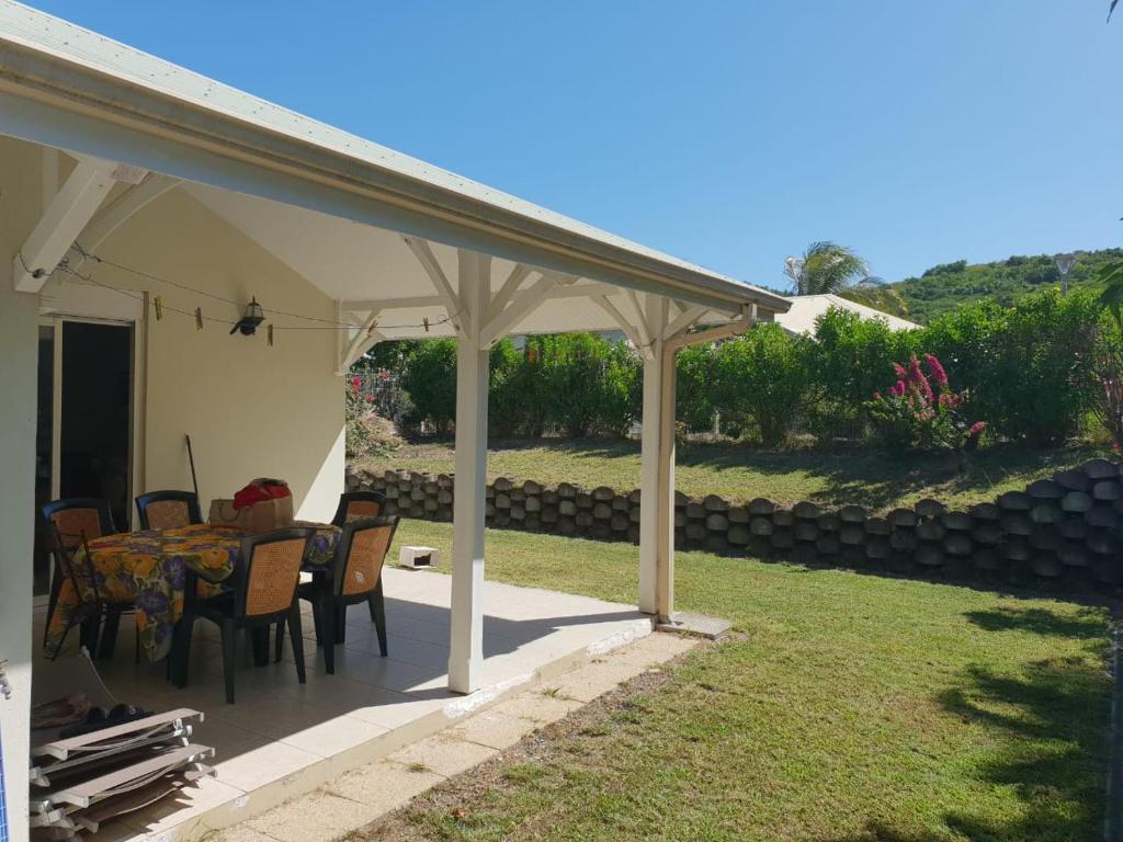 a patio with a table and chairs under a pavilion at Villa Les Flambloyants in Baréto