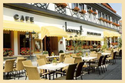 un restaurant avec des tables et des chaises en face d'un bâtiment dans l'établissement Hotel Kempf, à Dirmstein