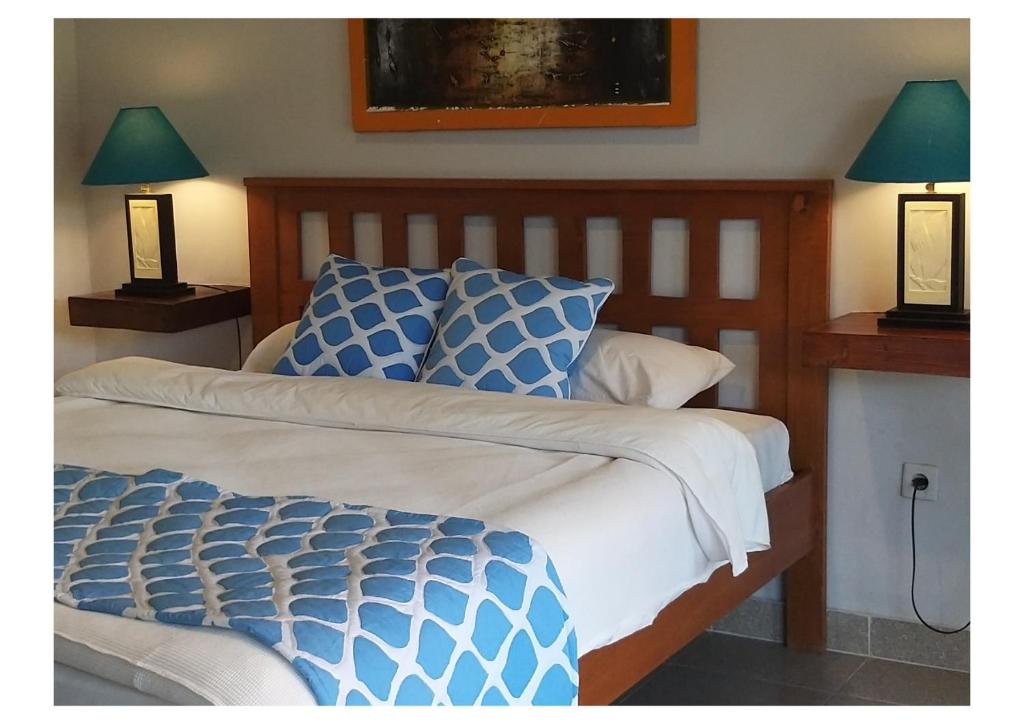 un lit avec une couette bleue et blanche et deux lampes dans l'établissement Tropical Beach Resort Sekongkang, à Sekongkang Bawa