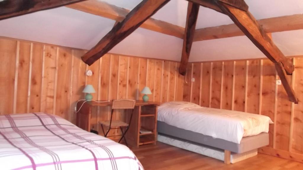 two beds in a room with wood paneling at Le Mas De La Siffleuse in Jaujac