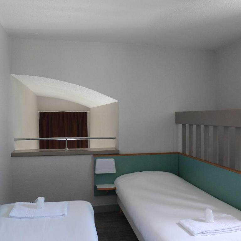 a small room with two beds and a window at B&B HOTEL La Rochelle Centre in La Rochelle