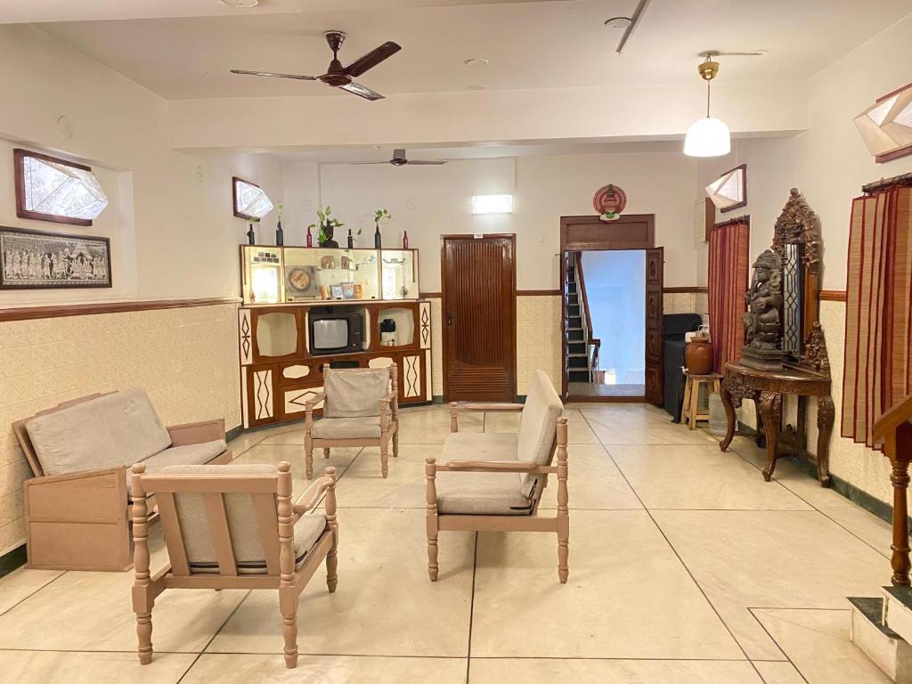 a living room with chairs and a couch and a tv at La Ruelle Guest House in Puducherry