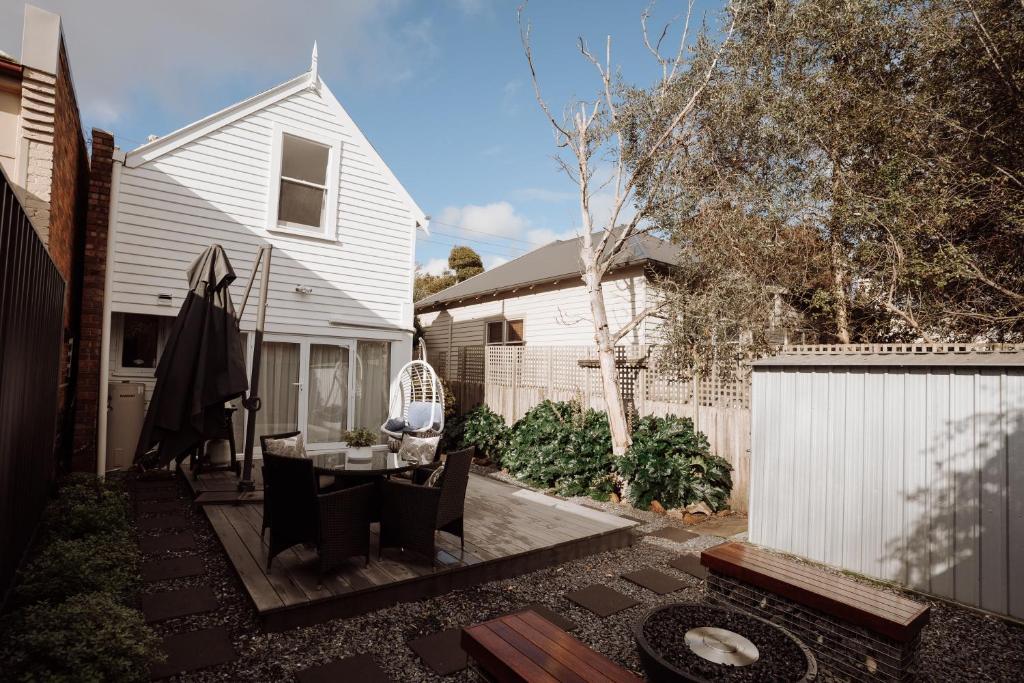 un cortile con un tavolo e sedie e una casa bianca di The Balfour, classic cottage in Launceston's Café Quarter a Launceston