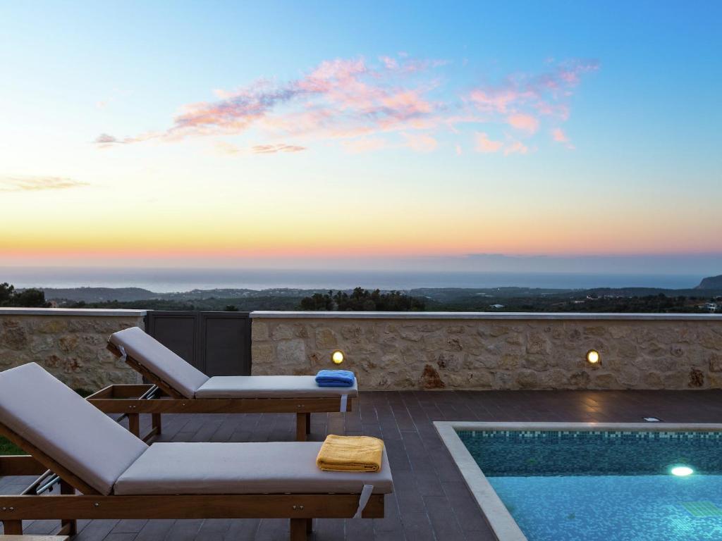 a villa with a swimming pool and a sunset at New villa with private pool, privacy, near sea and Arkadi monastery on NW coast in Roúpai