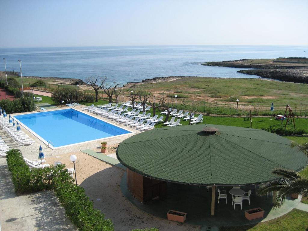 a swimming pool with an umbrella and chairs and the ocean at Residence Club Barbara in Ostuni