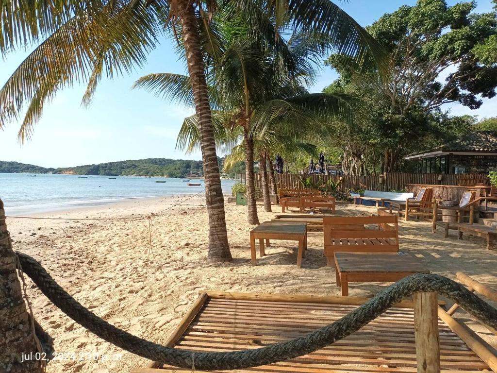 una playa de arena con bancos de madera y palmeras en Buzios tu refugio ideal, en Búzios