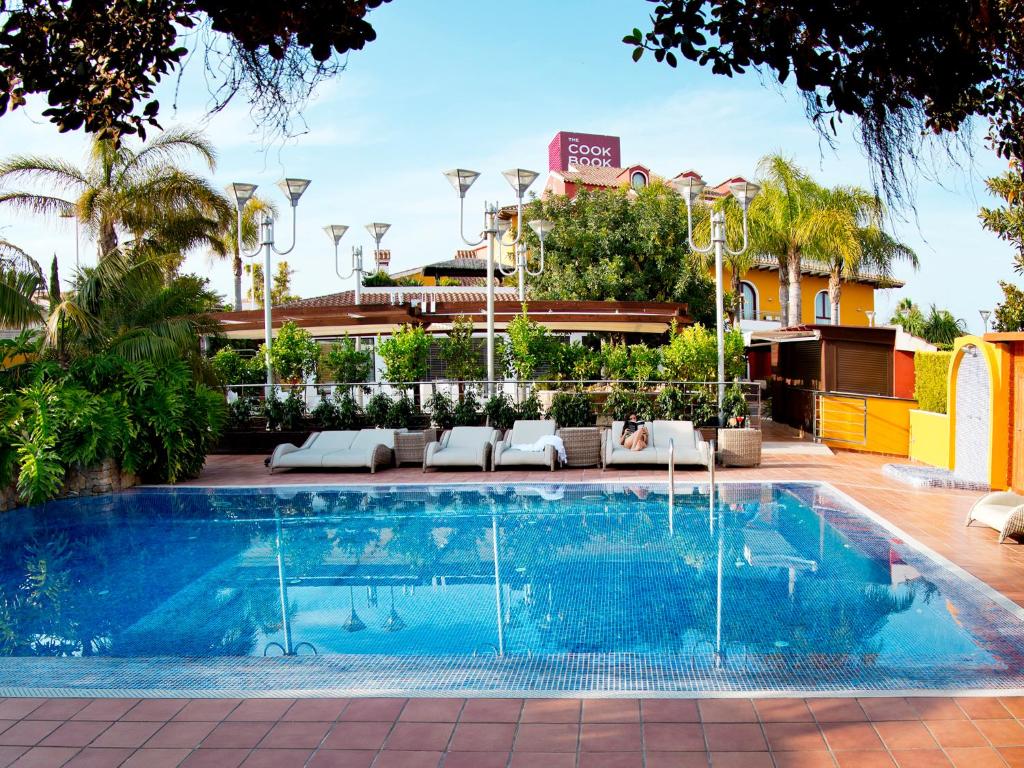 a swimming pool with chairs and a building at The Cookbook Gastro Boutique Hotel & SPA in Calpe
