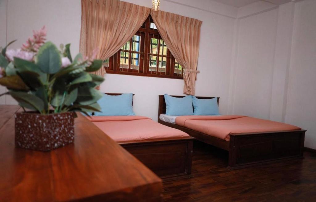 une chambre avec deux lits, une table et une fenêtre dans l'établissement Royal Palace Heritage, à Nuwara Eliya