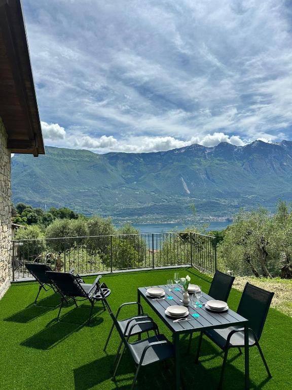 a table and chairs on a lawn with mountains in the background at Casa L'Oliver in Limone sul Garda