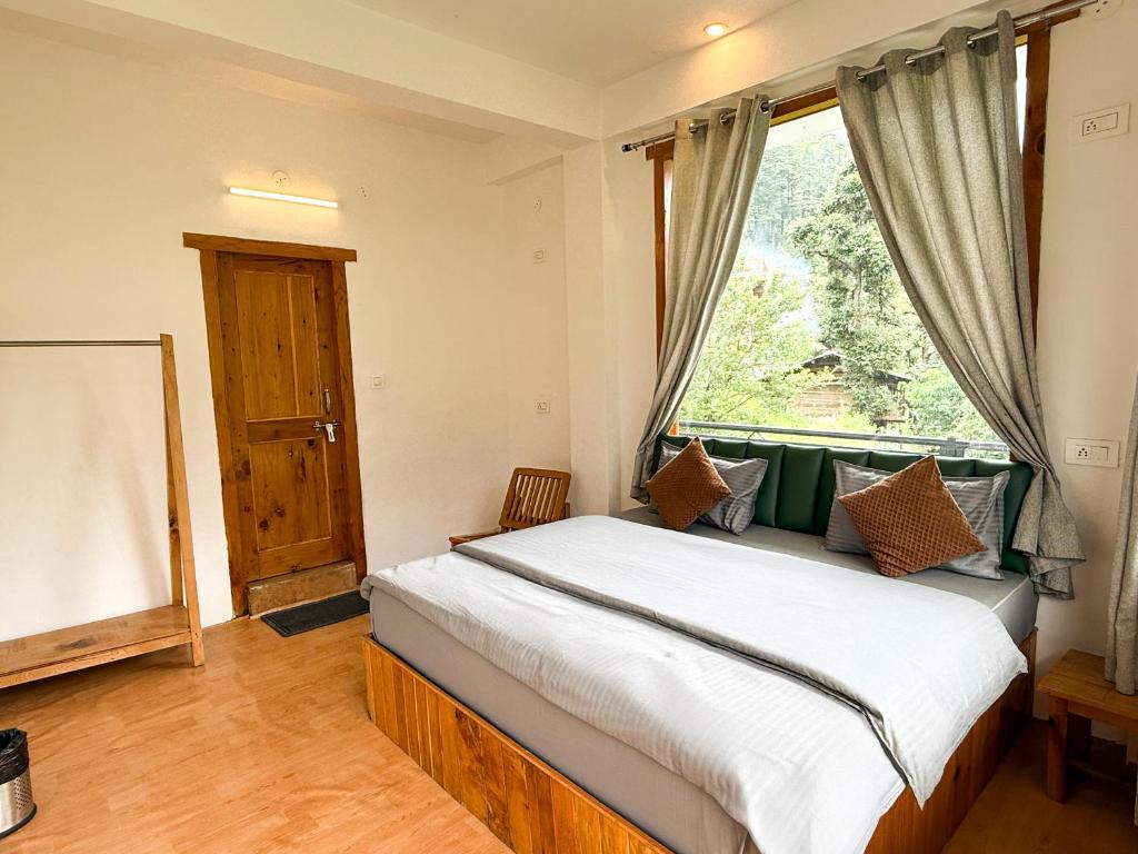 una camera da letto con un letto con una grande finestra di Young Monk Hostel & Cafe Jibhi a Jibhi