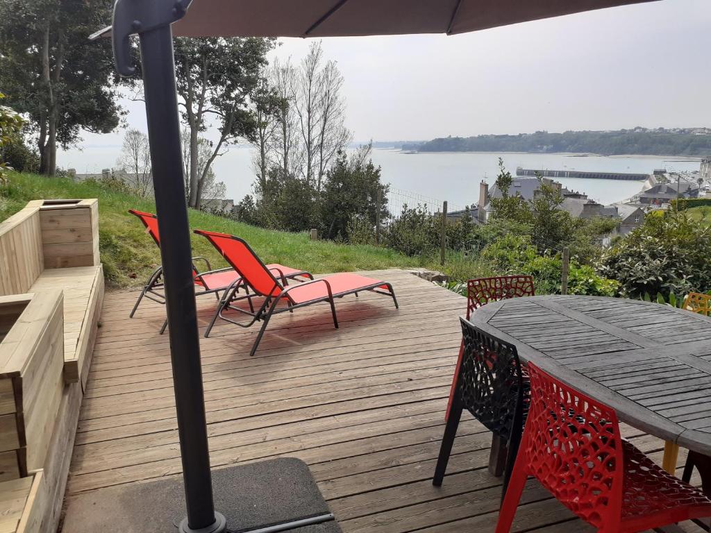 a deck with a table and chairs and an umbrella at Maison de charme cancalaise in Cancale
