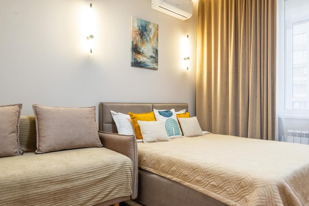 a bedroom with two beds and a couch at Светлая квартира-студия в 5-минутах от Мега Парк in Almaty