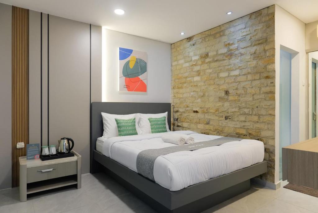 a bedroom with a large bed and a brick wall at Mono Coliving Kota Tua, Jakarta in Jakarta