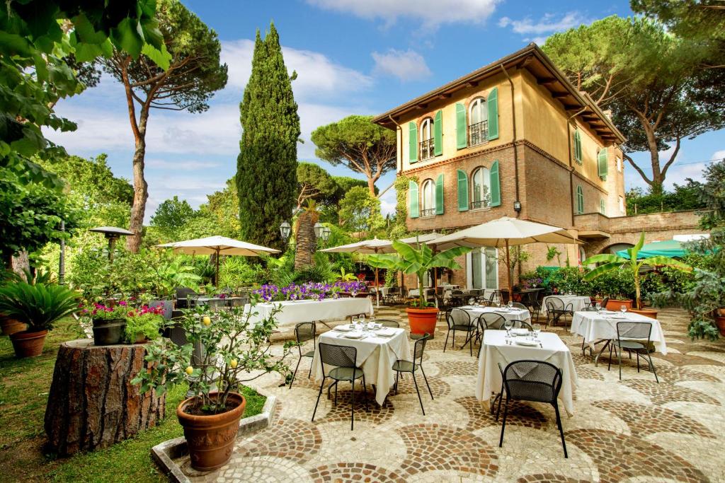 a patio with tables and chairs in front of a house at Hotel Verdeborgo in Grottaferrata