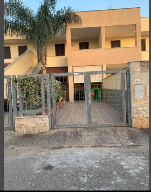 a gate in front of a building with a palm tree at CASA VACANZA Torre Lapillo PREMIUM in Torre Lapillo