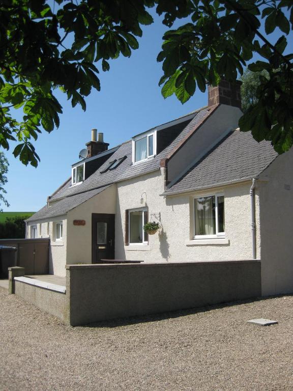 a white house with a black roof at Eastwood Cottage in Turriff