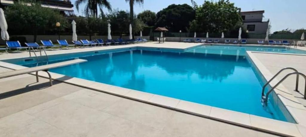une piscine avec des chaises bleues dans un hôtel dans l'établissement Relax Sea Capomulini Appartamento su due livelli, à Acireale