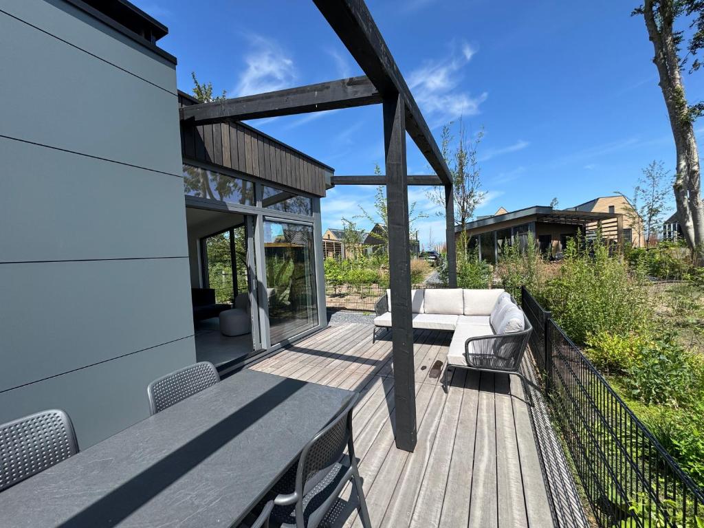 a wooden deck with a couch and chairs on it at Enkhuizer Strand Chalet Suydersee Huys Nr 462 in Enkhuizen