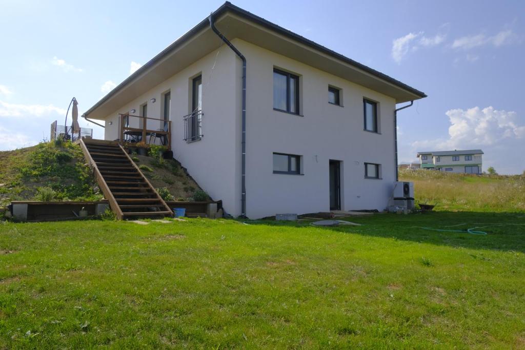 a white house with a grassy field in front of it at Červene maky - red poppies in Malý Slavkov