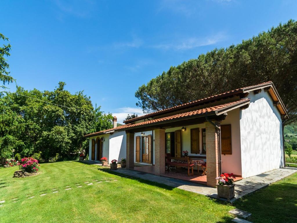 a small white house with a grass yard at Farmhouse in Tuscany with Panoramic Pool in Castiglion Fiorentino