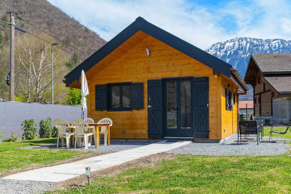 a small yellow house with a table and chairs at Chalet Cosy neuf sur terrain privé clôturé 600m2 in Faverges